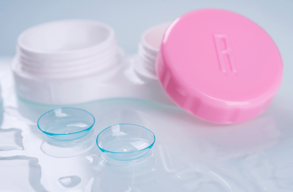 A pair of contact lenses sitting in contact lens solution, next to a contact lens case