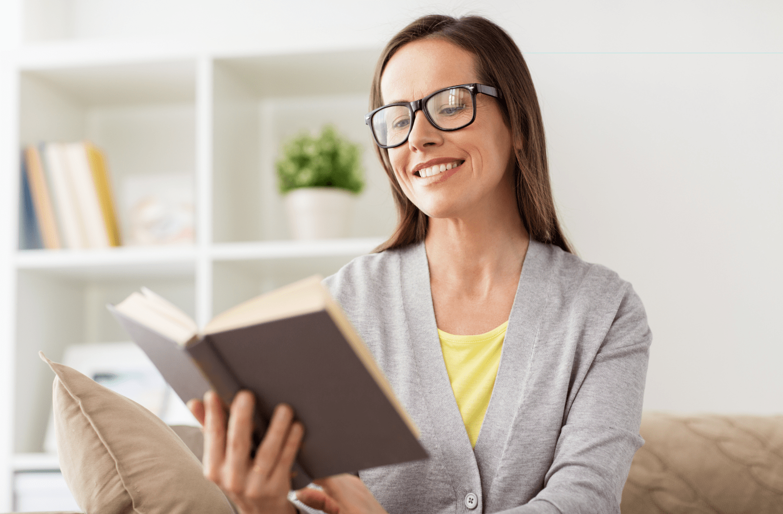 A woman using glasses to read a book in her living room