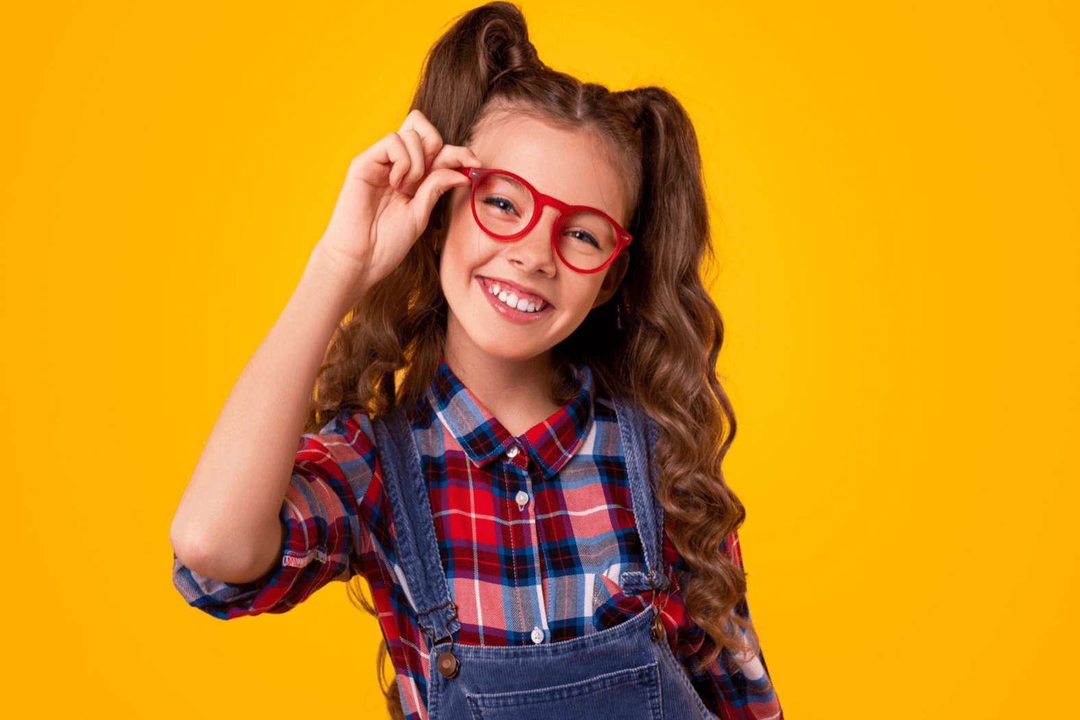 A young girl touching the edge of her glasses
