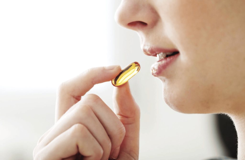 A Side -view close up of a girl taking omega-3 supplements