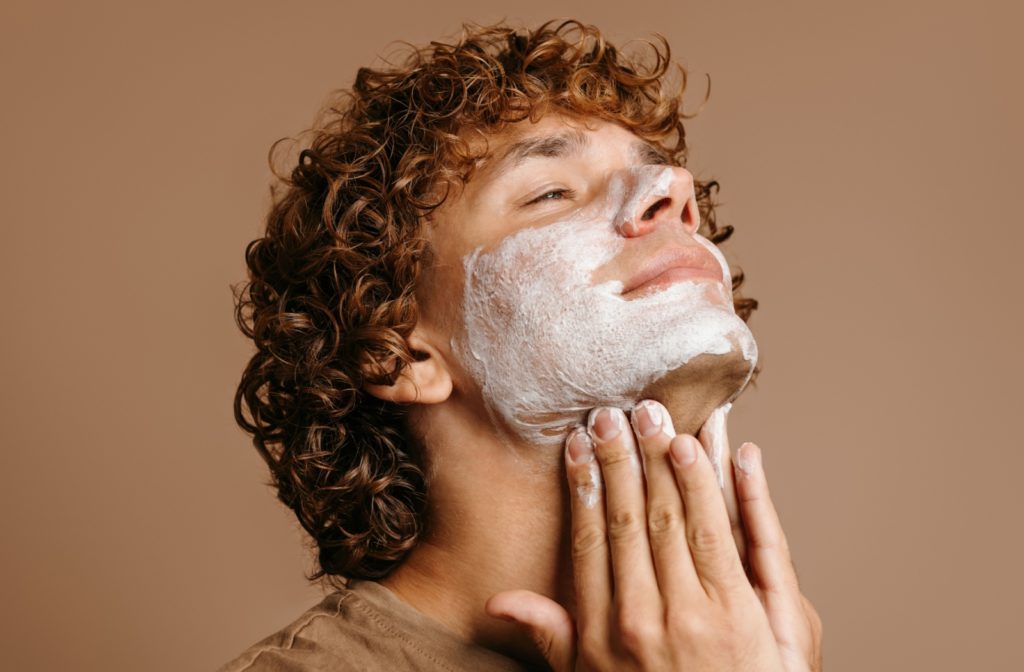 A young man washing his face with a facial cleanser.