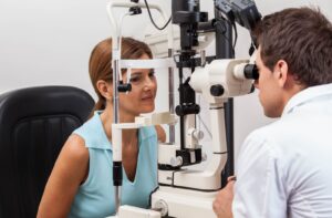 Person undergoing an eye exam using a slit lamp with an optometrist in a clinic setting