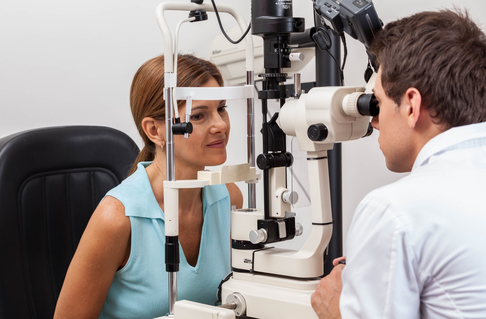 Person undergoing an eye exam using a slit lamp with an optometrist in a clinic setting