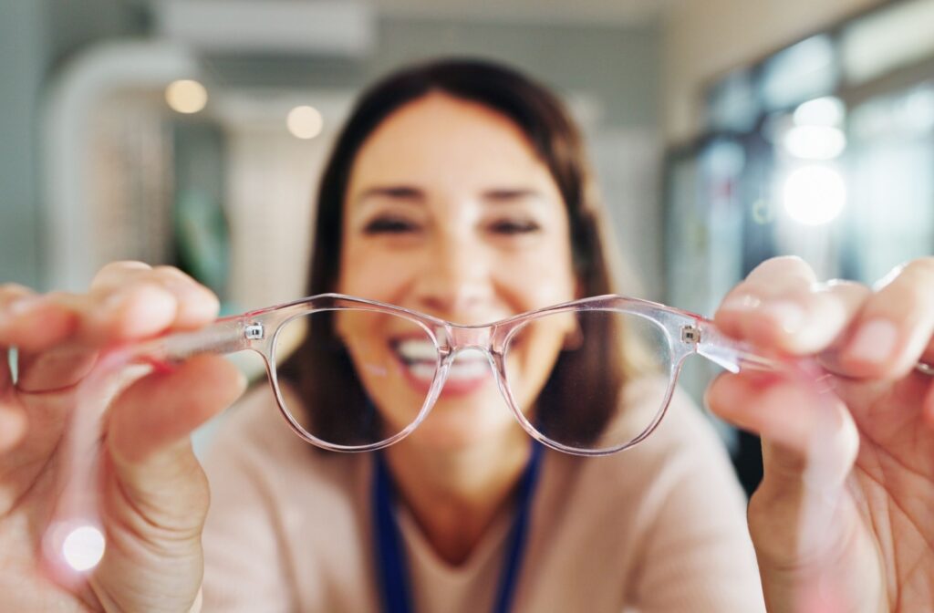 A person putting pink framed glasses on the viewer.
