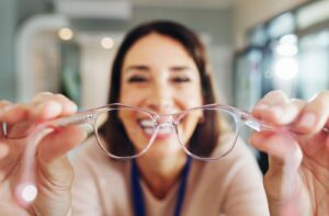 A person putting pink framed glasses on the viewer.