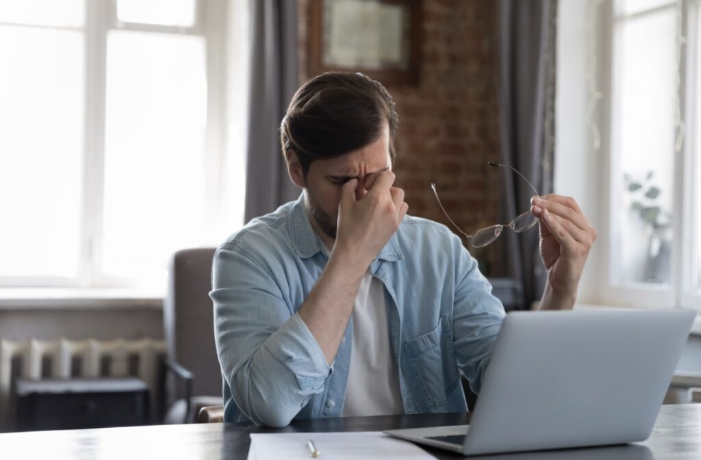 person removing glasses to rubbing their eyes that are irritated